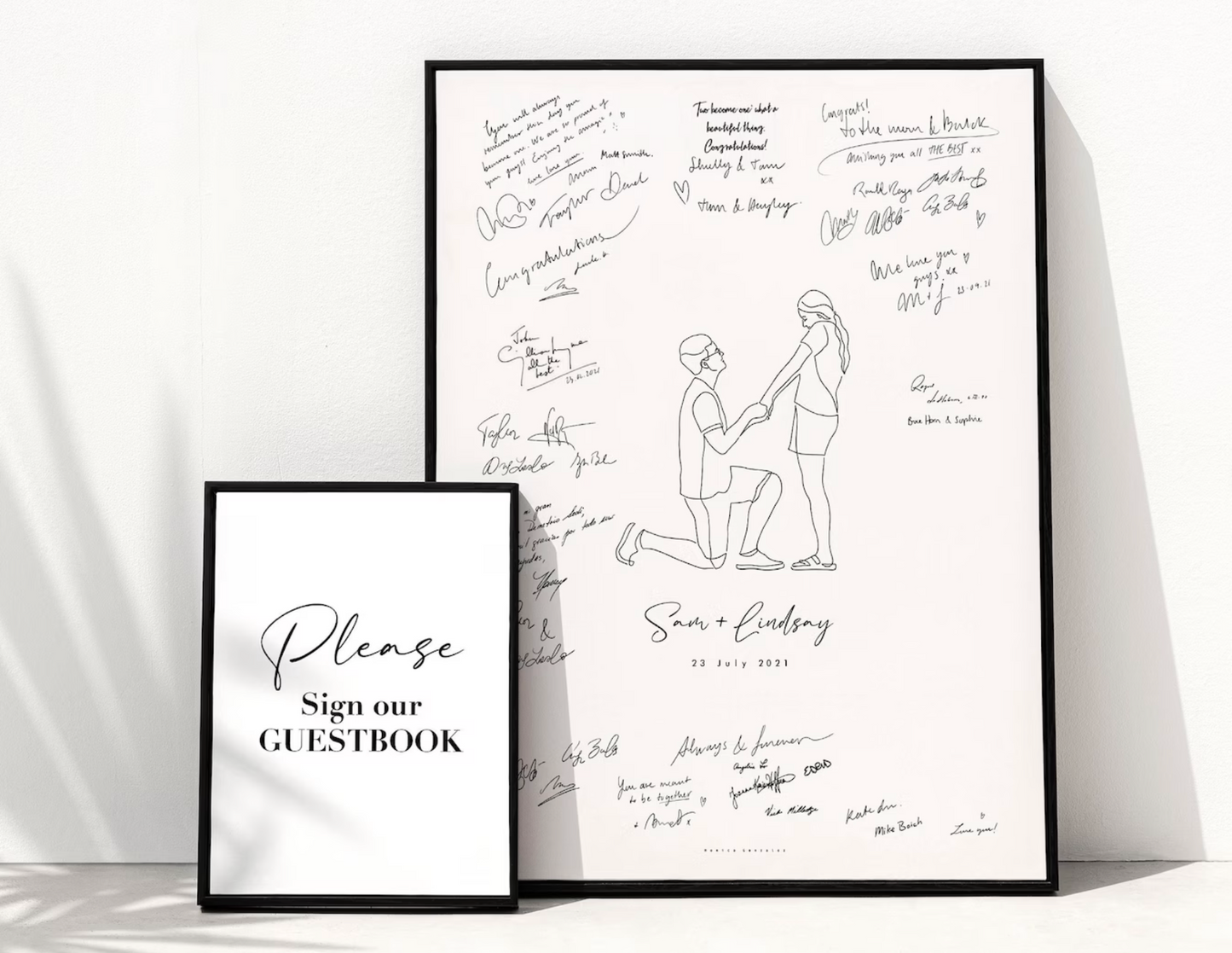 Framed guestbook with signatures and a couple illustration on a white background